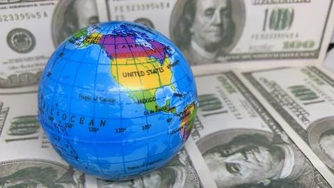 World globe resting on U.S. dollar banknotes, representing global trade Stock Photos
