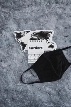 World map with face mask on it next to Borders text, travel industry after co Stock Photos
