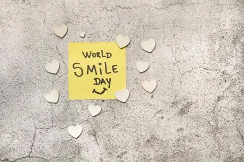 World smile day write in a paper note and white hearts on a gray stone Stock Illustration