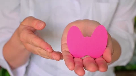 World Thyroid Day. Womens hands hold a paper form of the thyroid gland on a blue Stock Footage 195100545