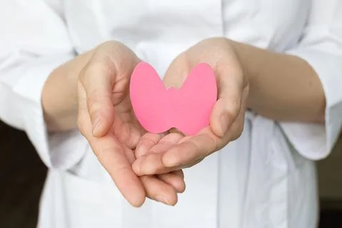 World Thyroid Day. Womens hands hold a paper form of the thyroid gland on a blue Stock Photos