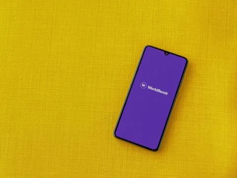 WorldRemit app launch screen on smartphone on yellow fabric background Stock Photos