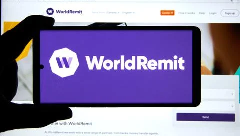 Worldremit application and logo on a cell phone over official web site Stock Photos