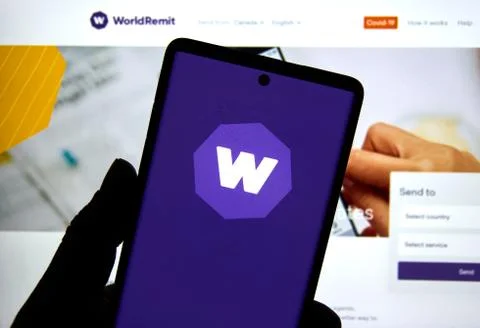Worldremit application and logo on a cell phone over official web site Stockfoto's