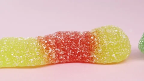 Worm shape jelly beans candies panning. Pink background, macro Stock Footage 155282134