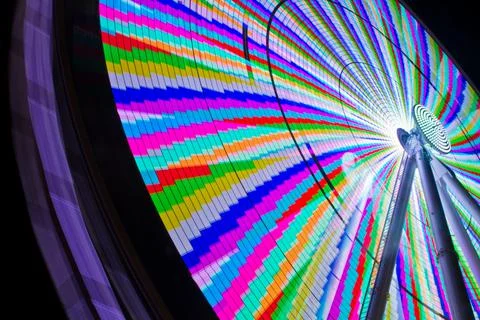 Worm's eye view of a ferris wheel lit up in a rainbow melange of colors Фото