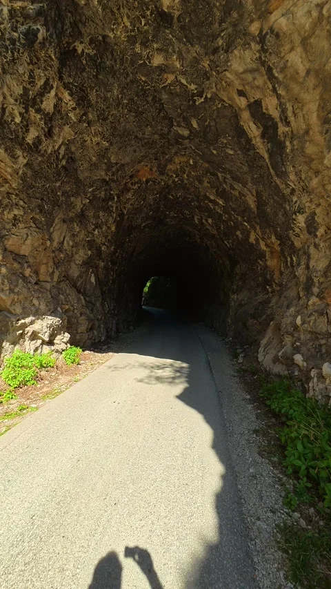 Worn asphalt leads into shadowed passage. Ovcar Kablar Gorge, Serbia. Vertical 스톡 동영상 334227021
