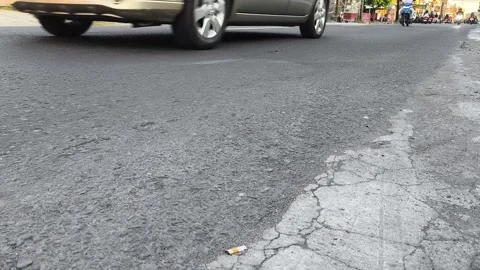 Worn asphalt road with visible cracks and a discarded cigarette Stock Footage 339565038