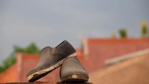 Worn black shoes on brick rooftop wall in Indonesia Stock Footage 312055500