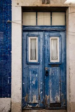 Worn blue door in Lisbon bordered by patterned ceramic tile Stock Photos