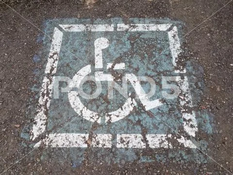 Worn blue wheelchair or handicap sign on asphalt Stock Photos
