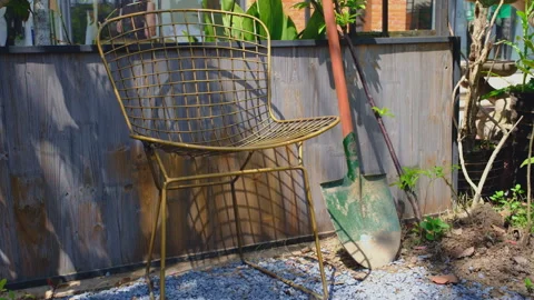 Worn Brass Wire Chair and Dirt-Streaked Gardening Shovel Stock Footage 333786860