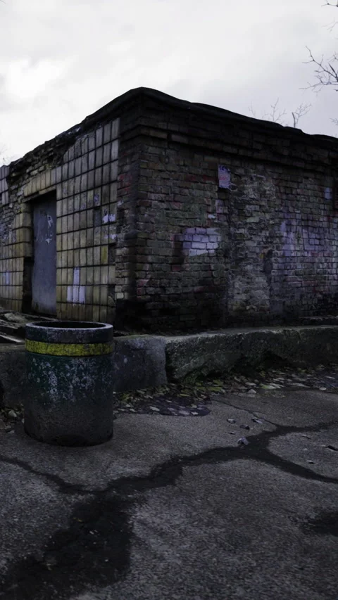 A worn brick building stands near a waste bin in a vacant lot Stock-Footage 336580859