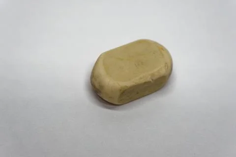 Worn brown laundry soap piece resting on a clean white surface 写真素材