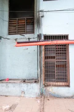 Worn building wall with iron window and red awning poles. Fotos de archivo