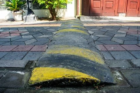A worn concrete speed bump with visible cracks and rough texture extends ac.. Stock Photos