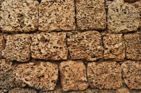 Worn down brown cobblestone rock on a textured wall Foto stock