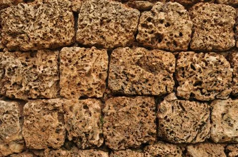 Worn down brown cobblestone rock on a textured wall Stock Photos