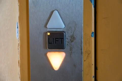 Worn Elevator Control Panel with Illuminated Down Arrow and Lift Button Stock Photos