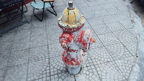 Worn fire hydrant standing on a patterned sidewalk in an urban street, showing Stock Footage 335644607