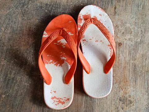 Worn flip flops with peeling white surface lying on a rough concrete floor Stock Photos