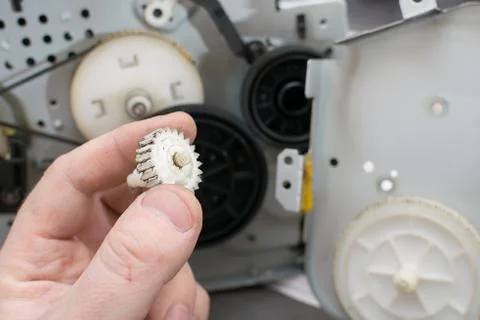 Worn gear from the printer reducer in the hands of the master, closeup Stock Photos