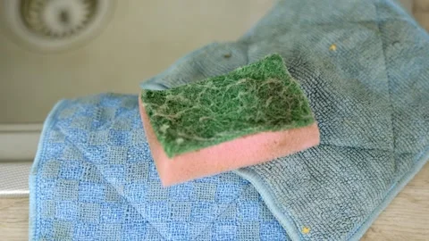 Worn Kitchen Sponge on Blue Cloth by Sink dolly in shot Stock Footage 301678421