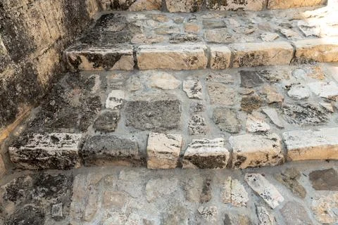Worn limestone steps of an ancient staircase with irregular stone blocks and Stock Photos