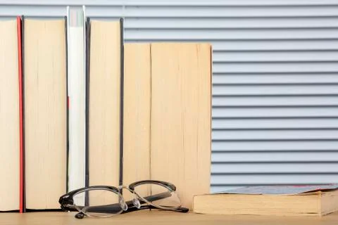 Worn looking reading books on a table with eye glasses Stock Photos