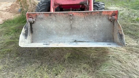 Worn metal loader bucket resting on grass near dirt pile Видео 338361708