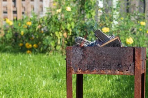 A worn-out barbecue with rust stands in the yard of the house against a backg Fotos de archivo
