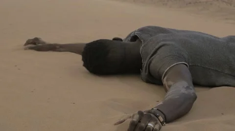 Worn-out black guy laying down on a desert sand Stock Footage 67558474