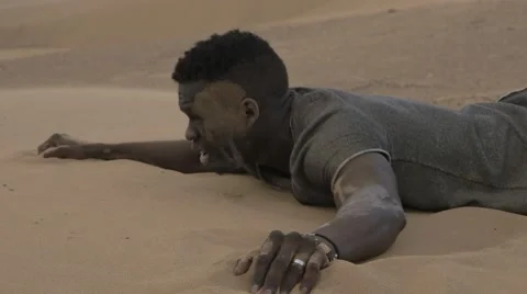 Worn-out black guy laying down on a desert sand Stock Footage 67558485