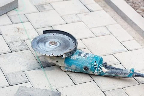 A worn-out diamond angle grinder lies on the paving slabs in front of the wor Stock Photos