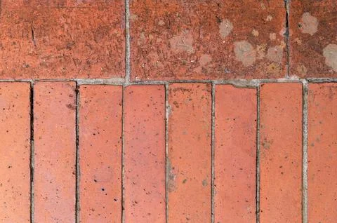 Worn red brick tiles aligned in row on outdoor floor surface Stock Photos