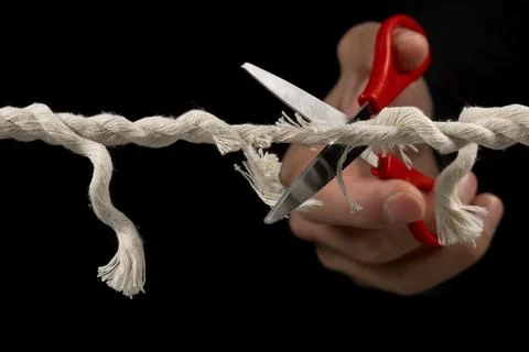 Worn rope ready to break, with scissors on black background. Stock-Fotos