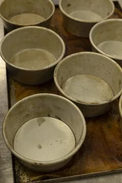 Worn round baking pans arranged on stained metal tray in commercial kitchen Stock Photos