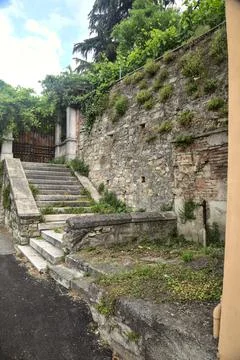 Worn stone staircase that leads to a rusty gate next to a stone wall on a clo Stock Photos