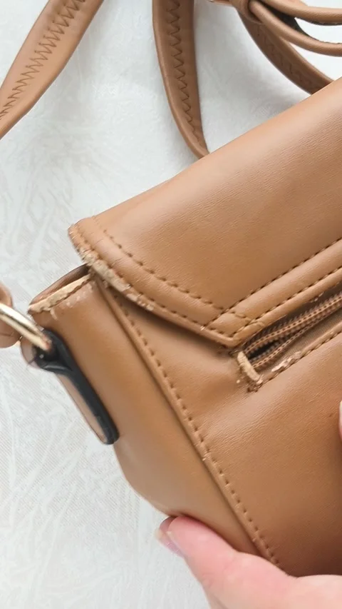 The worn strap of the bag is a close-up. A worn brown leather bag in the hands Stock Footage 316208702