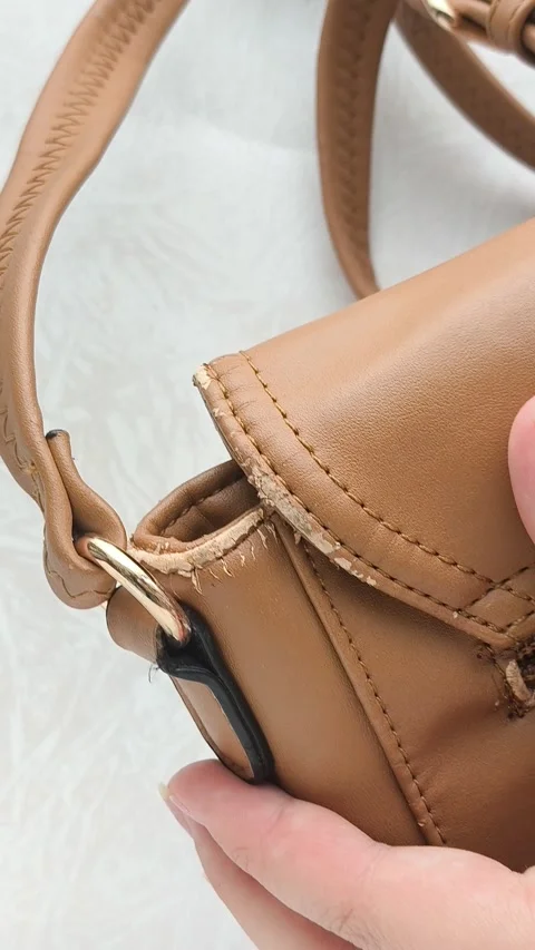 The worn strap of the bag is a close-up. A worn brown leather bag in the hands Stock Footage 316208712