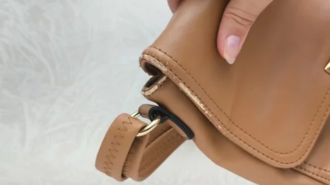 The worn strap of the bag is a close-up. A worn brown leather bag in the hands Stock Footage 316208957