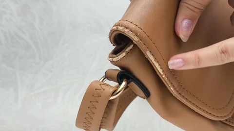 The worn strap of the bag is a close-up. A worn brown leather bag in the hands Stock Footage 316208996