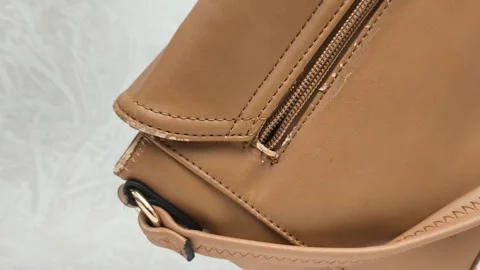 The worn strap of the bag is a close-up. A worn brown leather bag in the hands Stock Footage 316209046