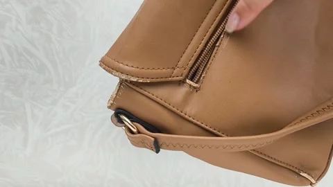The worn strap of the bag is a close-up. A worn brown leather bag in the hands Stock Footage 316209212
