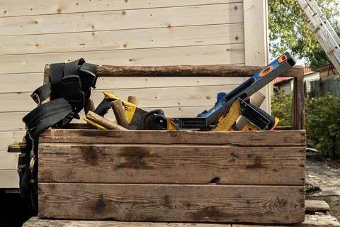 A worn toolbox with old tools against a wall, featuring levels, hammer, and 写真素材