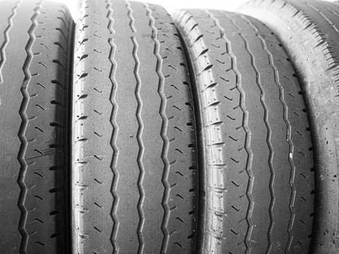 Worn tyres stacked side by side sidelit Stock Photos