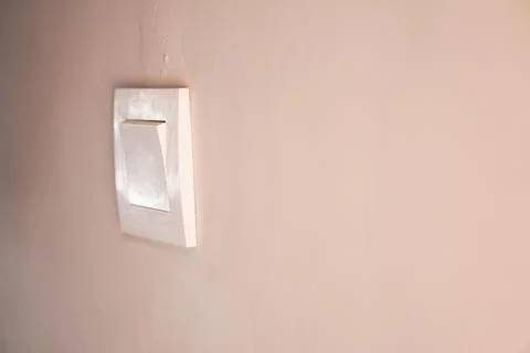 Worn white light switch on beige wall Stock Photos