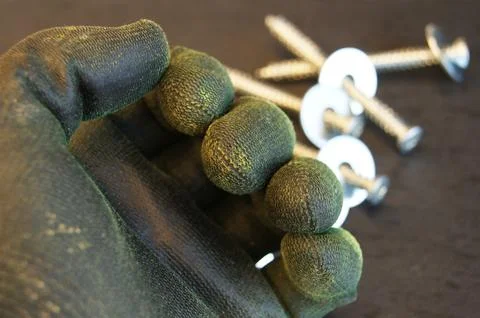 A worn work glove is put on the builder's hand Stock Photos