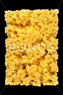 Worn yellow sponge for washing dishes on black background, abstract backgroun Stock Photos