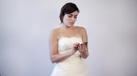 Worried bride to be texting on her cellphone, wearing wedding dress Stock Footage 43094482